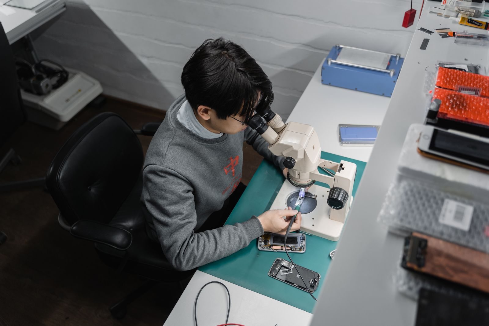 A technician inspecting a smartphone at a workbench